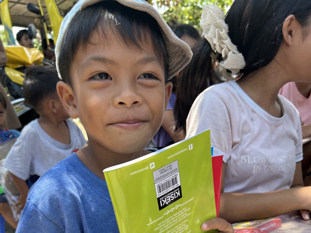 Children holding notebooks and school supplies given out by the church